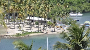 Una playa con palmeras, un bote y un edificio de techo blanco.