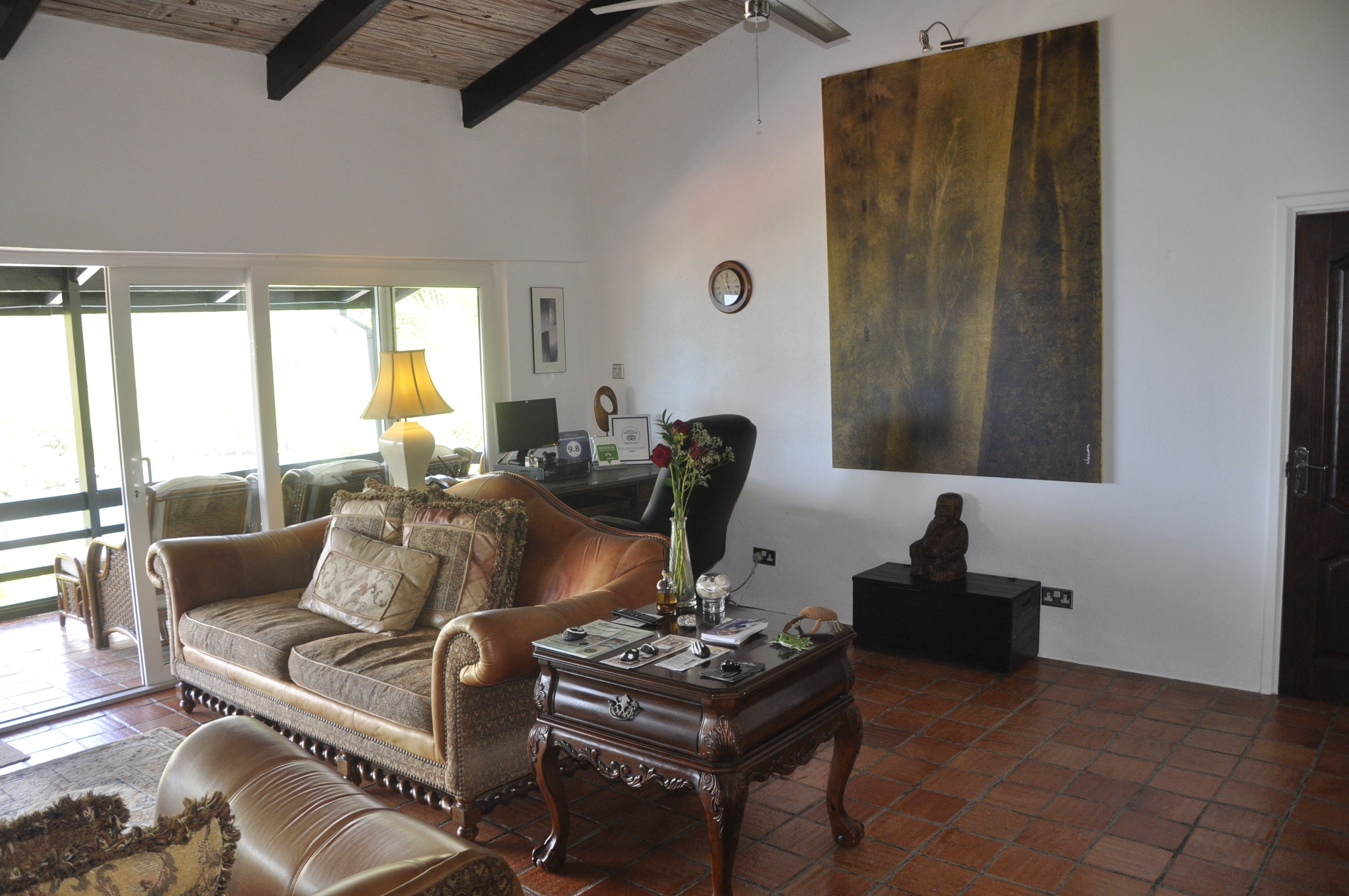 Uma sala de estar com um sofá de couro, uma mesa de centro e um grande quadro abstrato na parede.