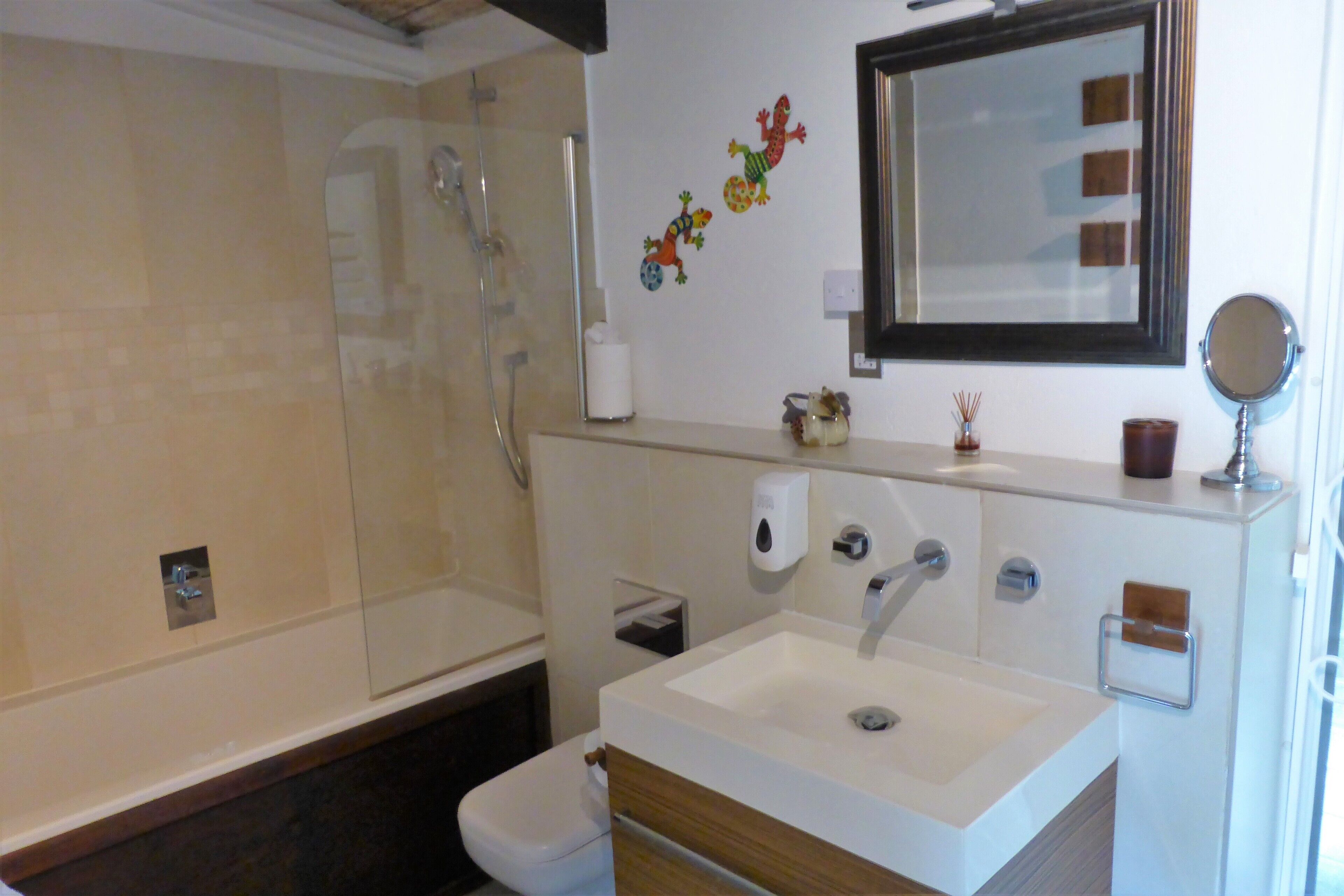 Un baño moderno con cabina de ducha de vidrio, un lavabo blanco con mueble de madera y pegatinas decorativas en la pared.