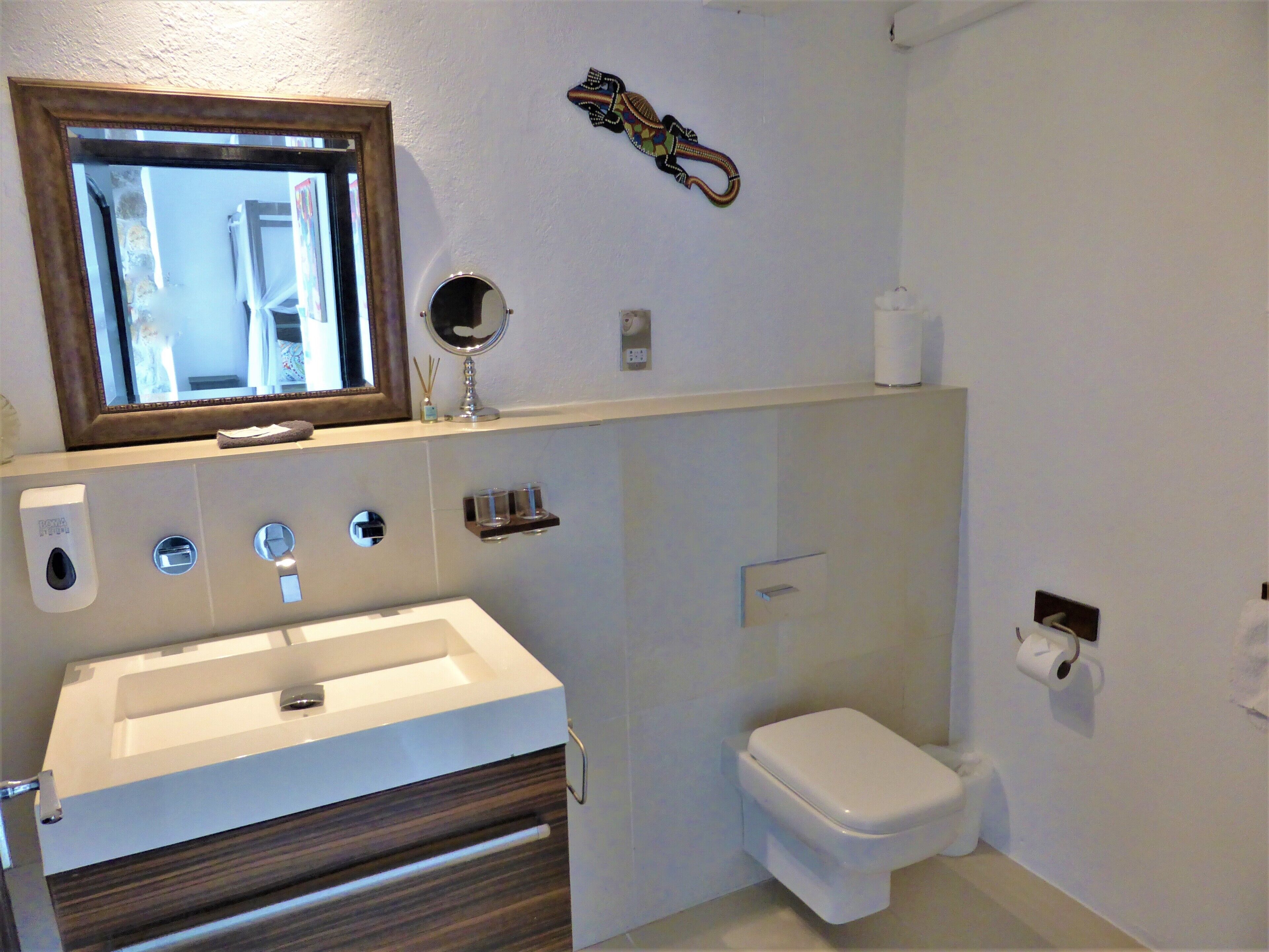 Une salle de bain avec un lavabo blanc, un miroir et des toilettes.
