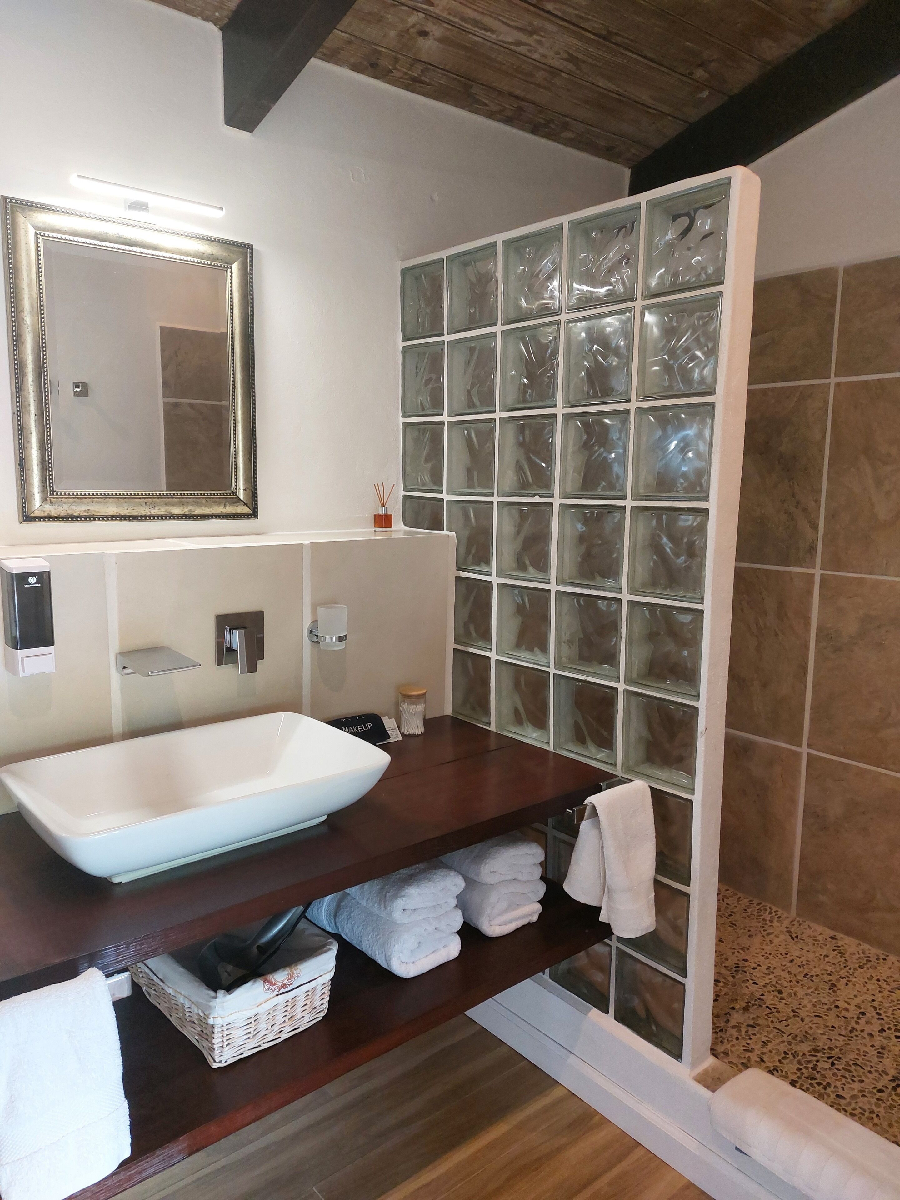 Une salle de bain avec un grand miroir, un lavabo blanc, une douche en verre et un meuble-lavabo en bois.