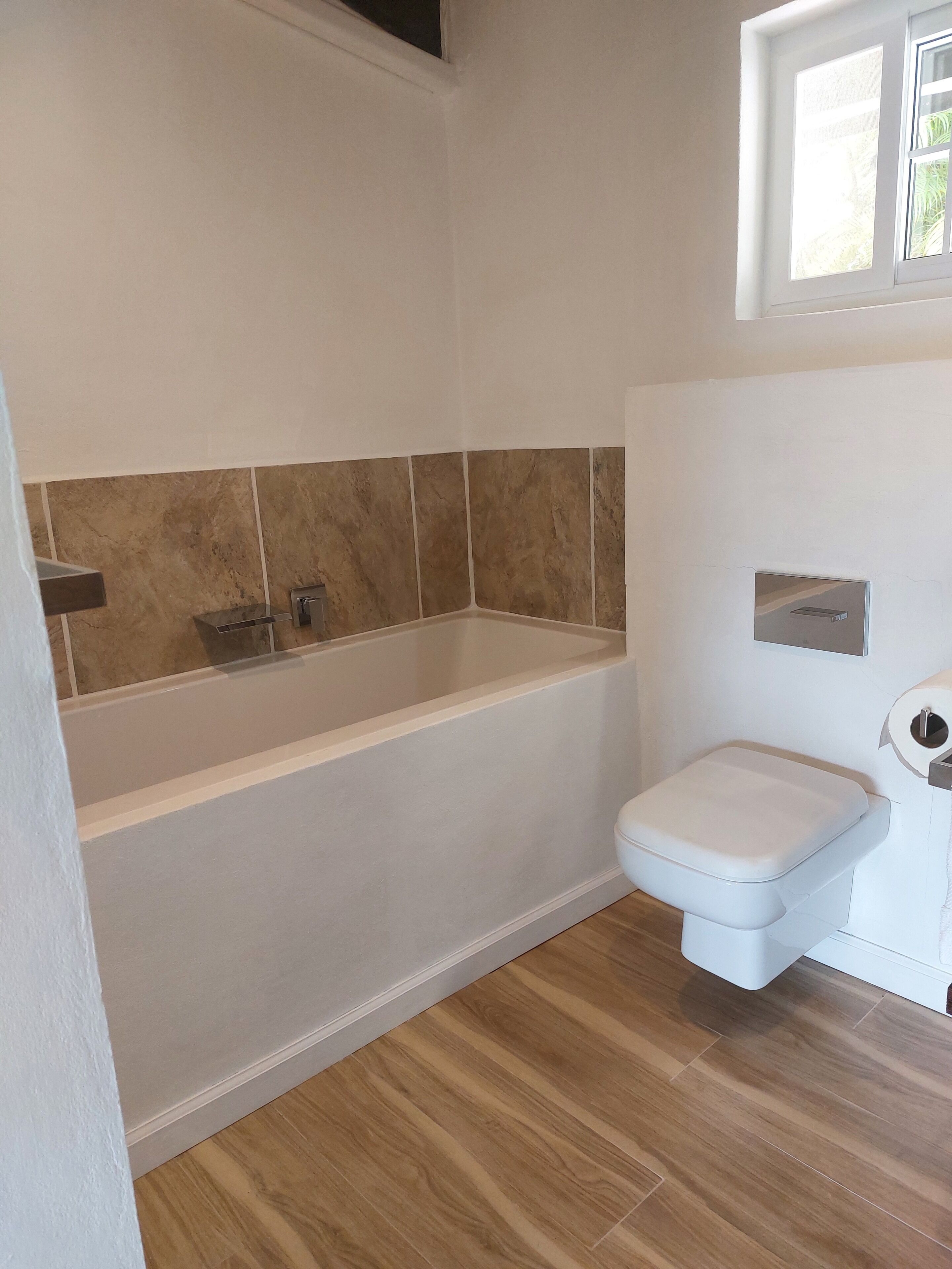 A bathroom with a bathtub, toilet, and a shower area.