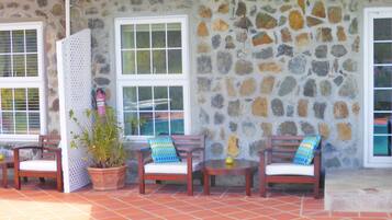 Un espacio al aire libre con paredes de piedra, mobiliario de madera y una planta en maceta.