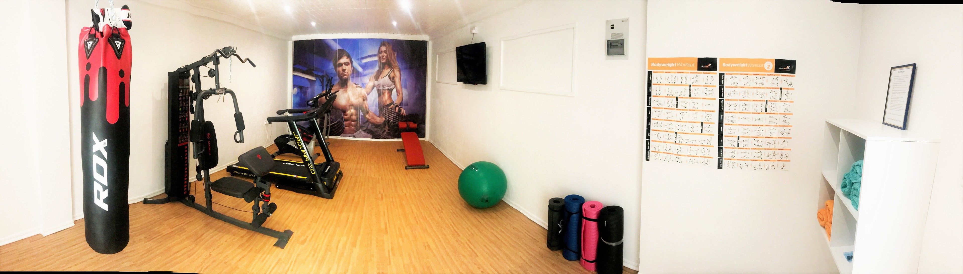 Un gimnasio en casa con cinta de correr, saco de boxeo y equipo de ejercicio.