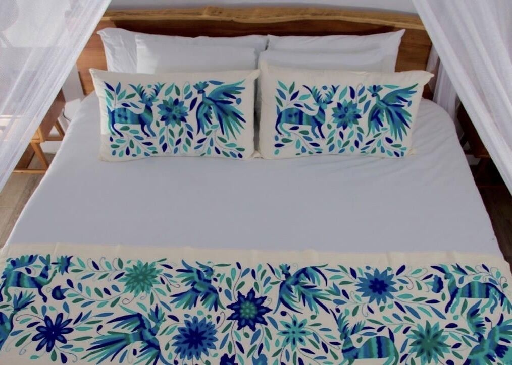 A bed with white bedding and two decorative pillows with blue floral patterns.