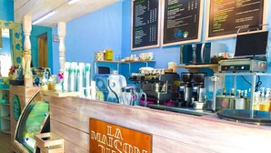 Interior de una cafetería con mostrador de madera, pizarras con la carta y equipo para preparar café.