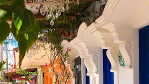 Un área de estar al aire libre con mesas y sillas de madera, un candelabro y decoración azul y blanca.