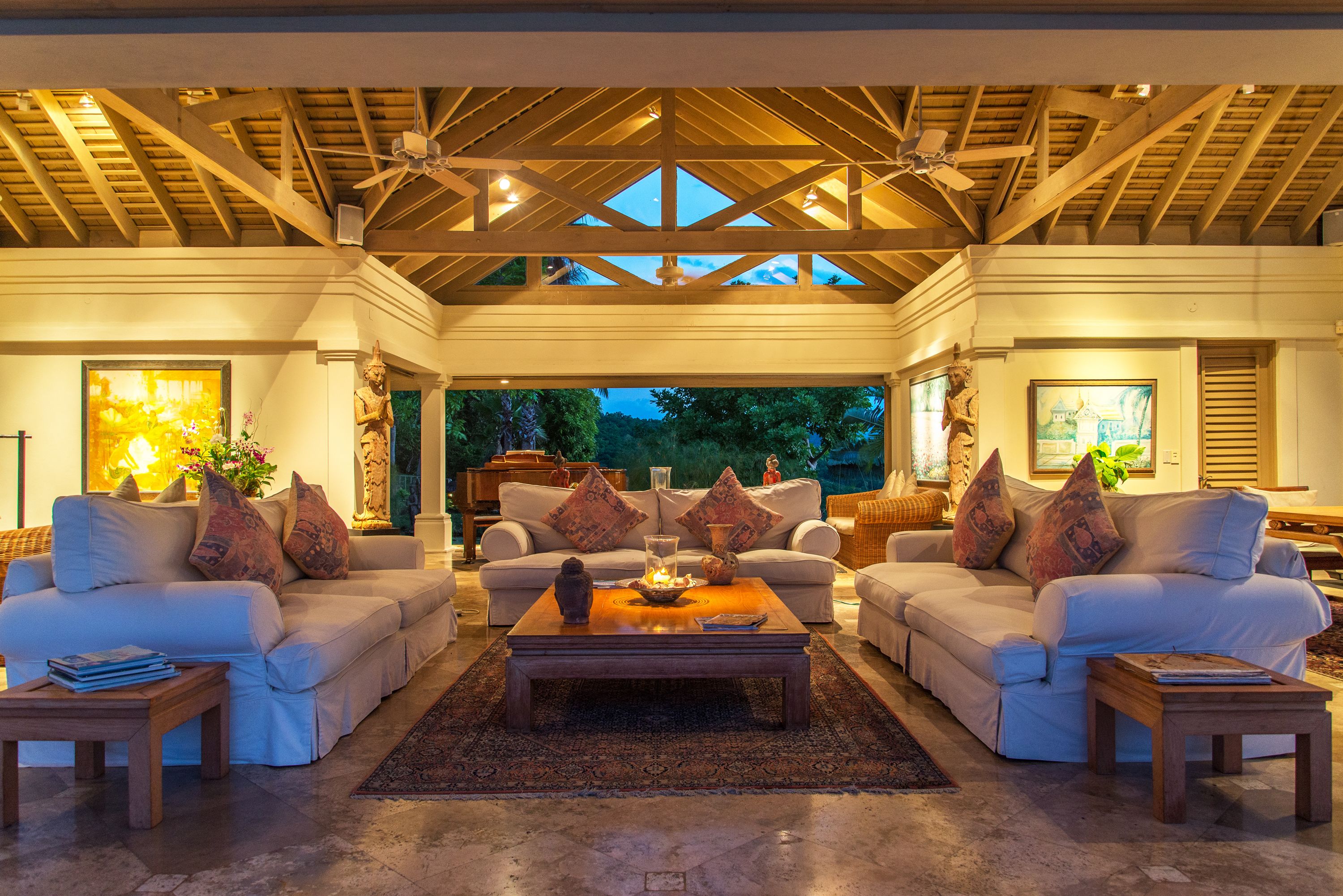 Ein geräumiges Wohnzimmer mit hohen Decken und Holzbalken, ausgestattet mit zwei Sofas und einem Couchtisch, mit Blick ins Freie.