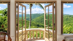 Une chambre avec vue sur de verdoyantes collines et un palmier.
