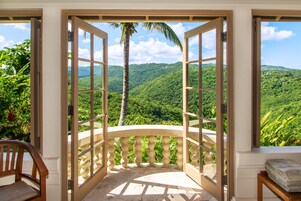 Una habitación con vista a ondulantes colinas verdes y una palmera.