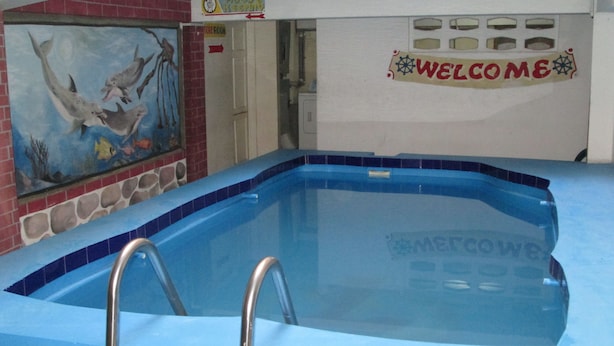 A swimming pool with a 'Welcome' sign, a mural of dolphins, and a 'No Diving' sign. - Seven Stars Hotel (Port-au-Prince)