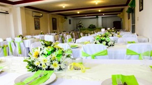 A banquet hall with round tables, each set with white tablecloths, green sashes, and floral centerpieces. - Seven Stars Hotel (Port-au-Prince)