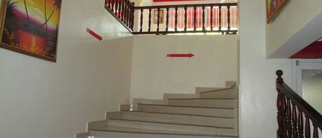 A staircase with a wooden railing, a ceiling fan, and red accents on the walls.