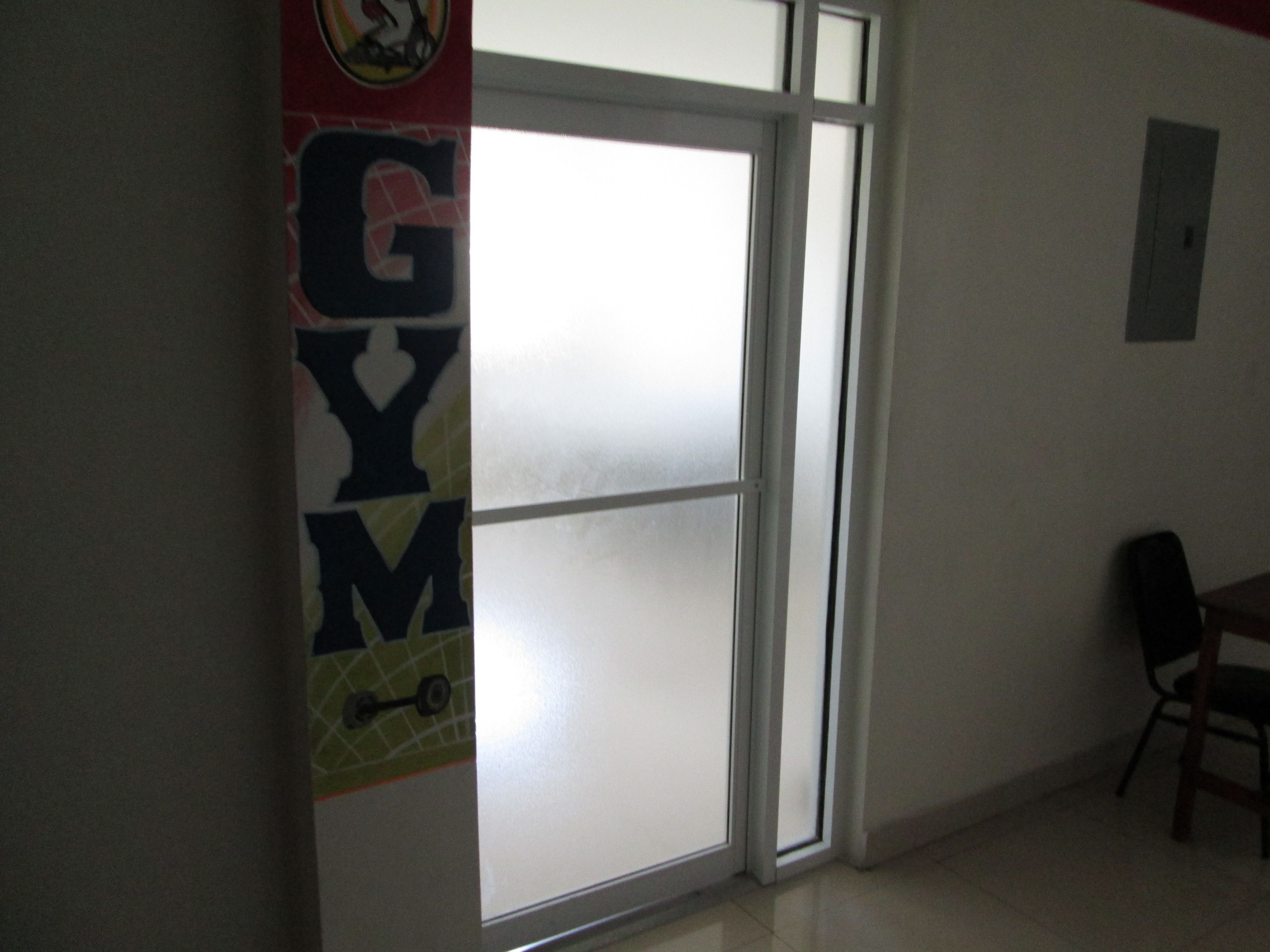 A room with a large window, a door, and a wall-mounted light switch.