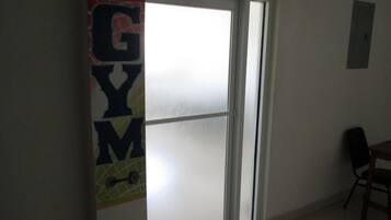 A room with a large window, a door, and a wall-mounted light switch.