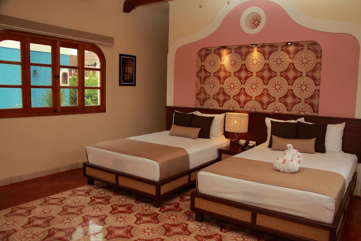 Une chambre d’hôtel avec deux lits, un sol à motifs, une grande fenêtre et un mur décoratif.