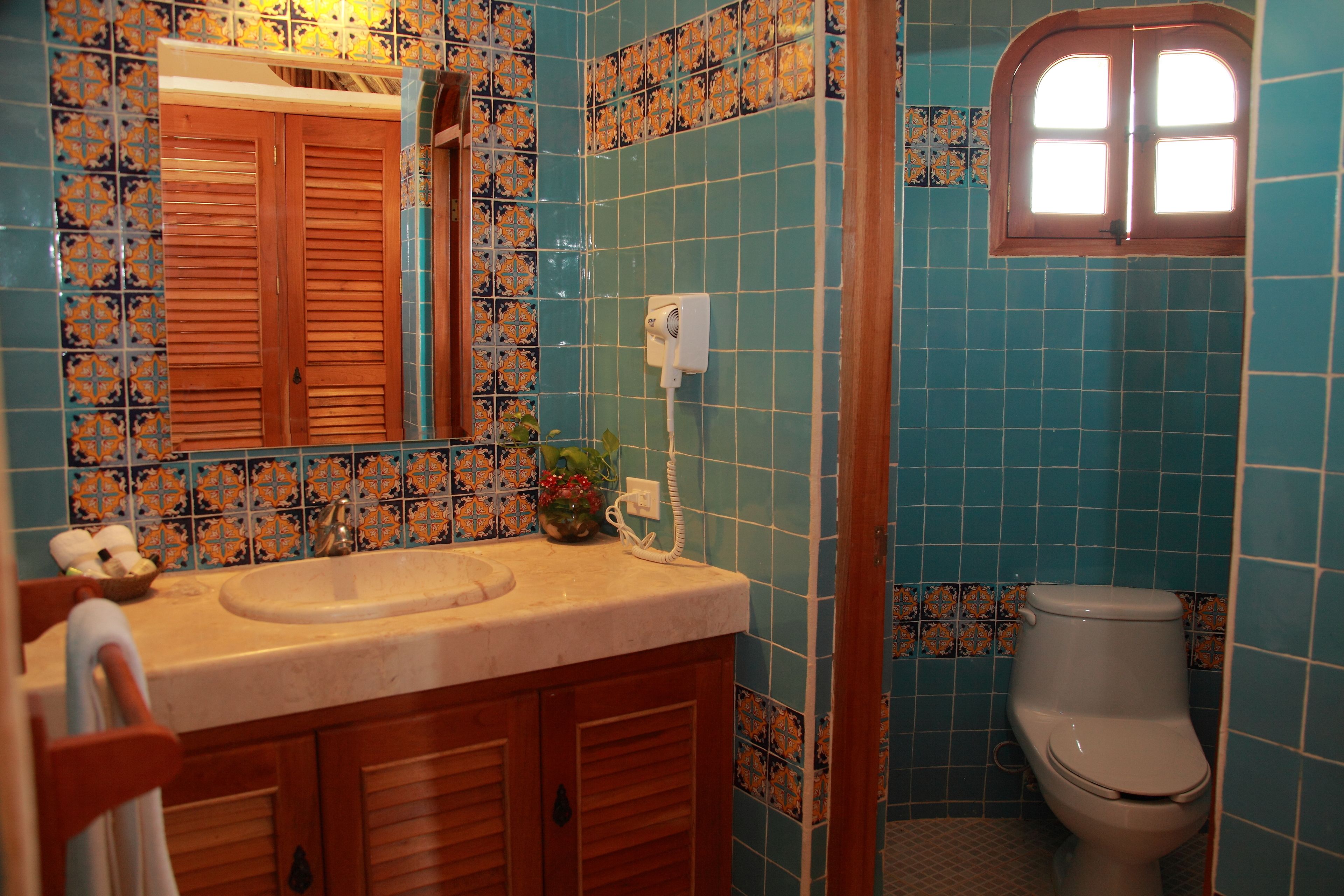 Un baño con lavamanos, espejo e inodoro.