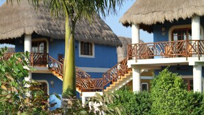 Ein Resort mit strohgedeckten Gebäuden, einer Treppe und üppiger Vegetation.