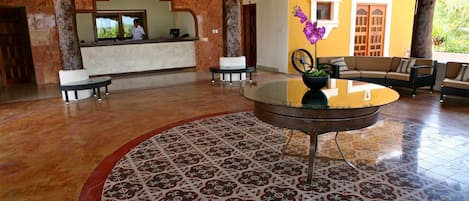 Un vestíbulo con mostrador de recepción, zona de estar y baldosas de suelo con diseño.