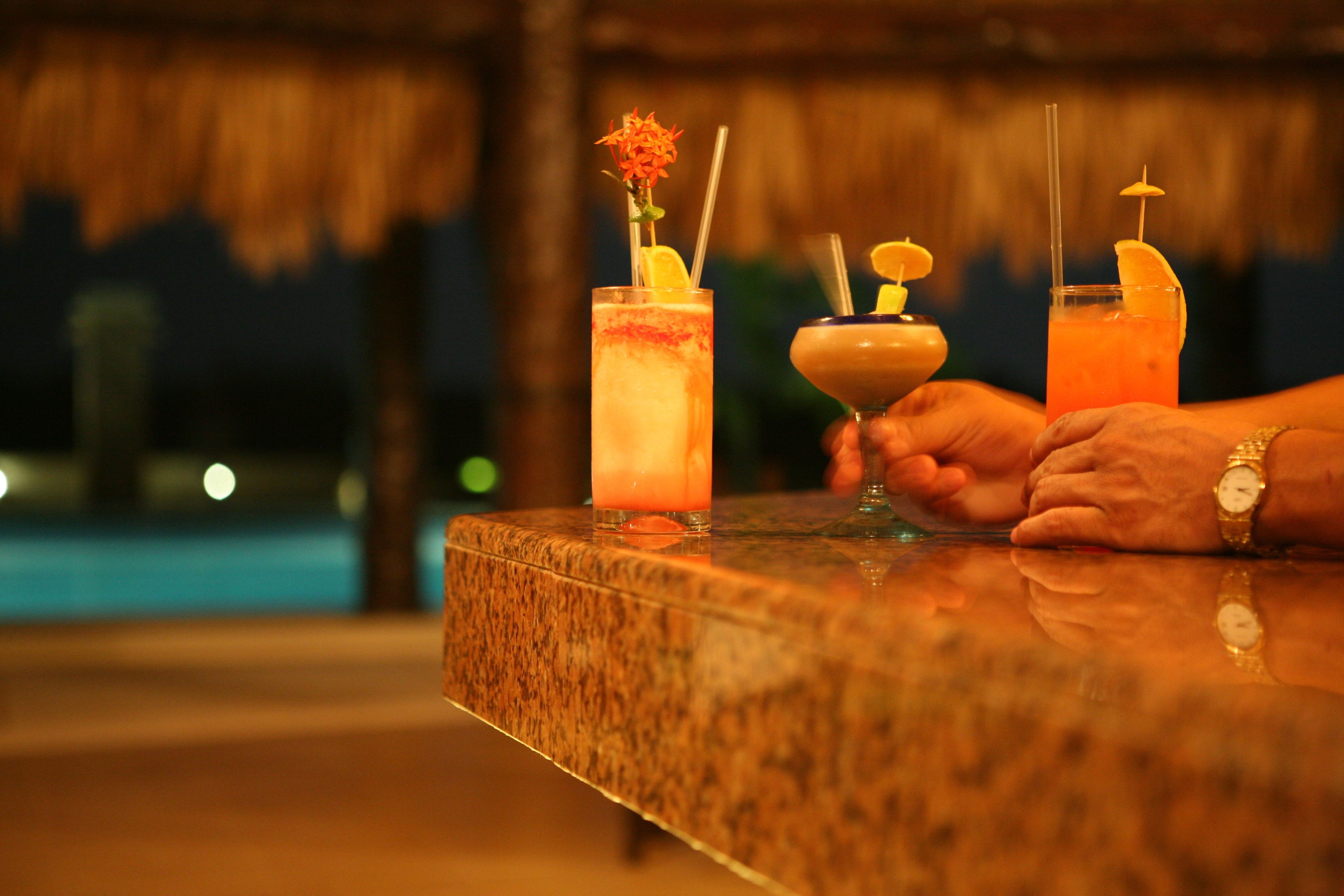 Una barra con tres bebidas, cada una adornada con una flor y un gajo de limón.