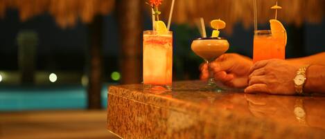 Una barra con tres bebidas, cada una adornada con una flor y un gajo de limón.