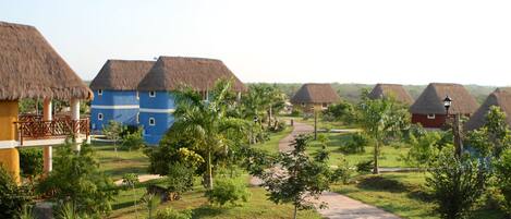 A resort with thatched-roof cottages, a central pathway, and lush greenery.