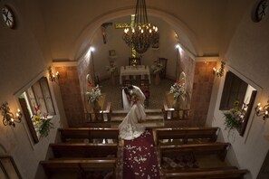 An interior view of a church with wooden pews, a central aisle, and a chandelier. - Cenotes Resort at Hacienda Sotuta de Peón (Timucuy)