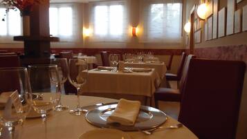 Interior de restaurante con mesas preparadas para comer, incluyendo platos, vasos y cubiertos.