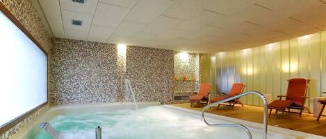 Een hottub met een betegelde mozaïekwand, houten vloer en twee oranje loungestoelen.