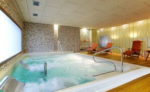Un jacuzzi con pared de mosaico, suelo de madera y dos sillones anaranjados.