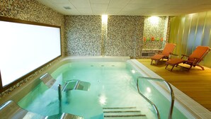 Ein Wellnessbereich mit einer großen Whirlwanne, zwei Liegestühlen und einer Wand mit Mosaikfliesen.