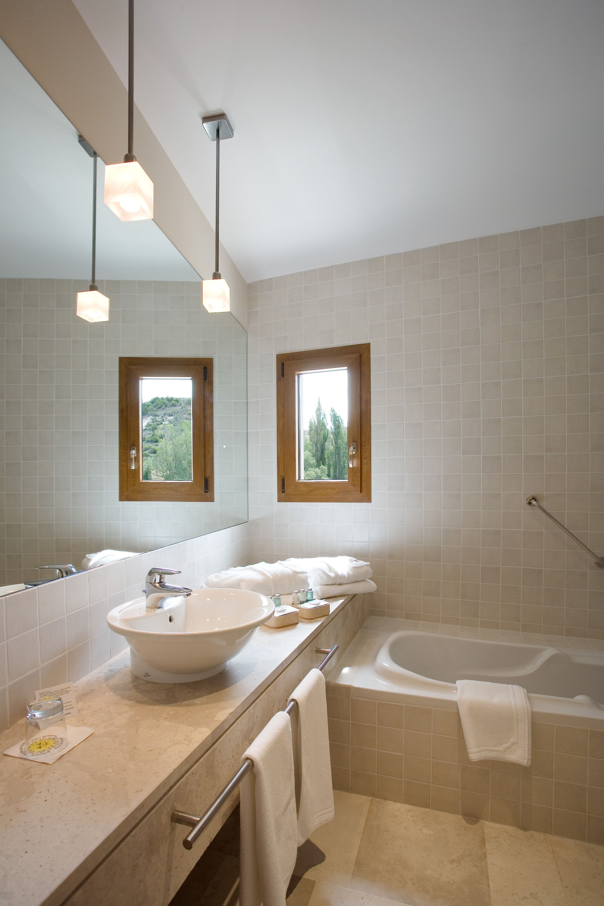 Un baño moderno con un lavamanos grande, una bañera y dos ventanas.