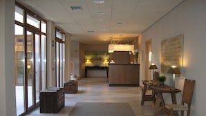 Eine Hotelhalle mit einer Rezeption, einer hölzernen Bank und einem Essbereich mit Stühlen und einem Tisch.