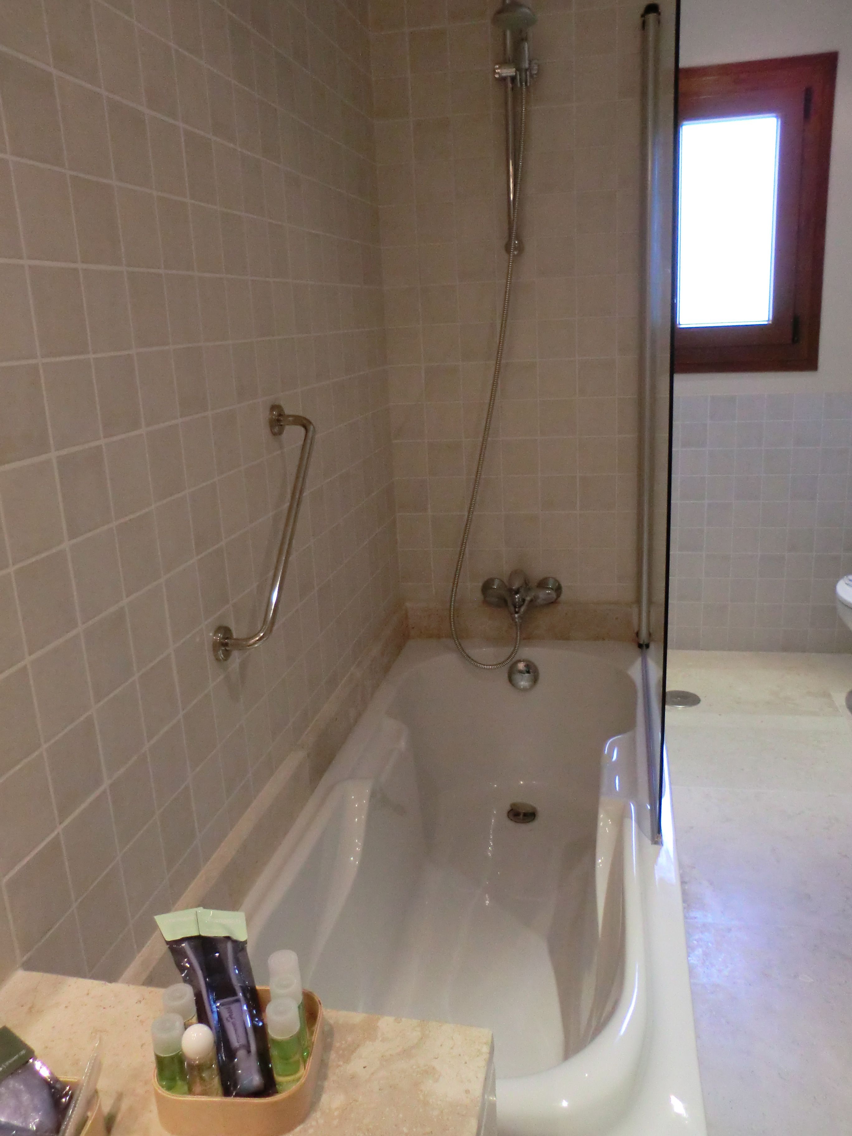 Een badkamer met een bad, een douche en een raam.