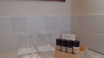 A bathroom counter with four bottles of hair care products, two empty glasses, and a small white container.