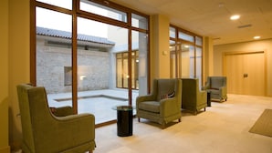 Eine Hotelhalle mit Sitzgelegenheiten, großen Fenstern und Blick auf das äußere Gebäude.