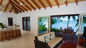 Amplia sala de estar con sofá, mesa de madera y zona de cocina con mostrador tipo bar y taburetes.