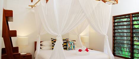 A bedroom with a four-poster bed, a wooden nightstand, a bedside table, and a window with blinds.