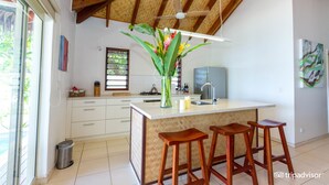 Una cocina moderna con una isla grande, taburetes de madera y un ventilador de techo.