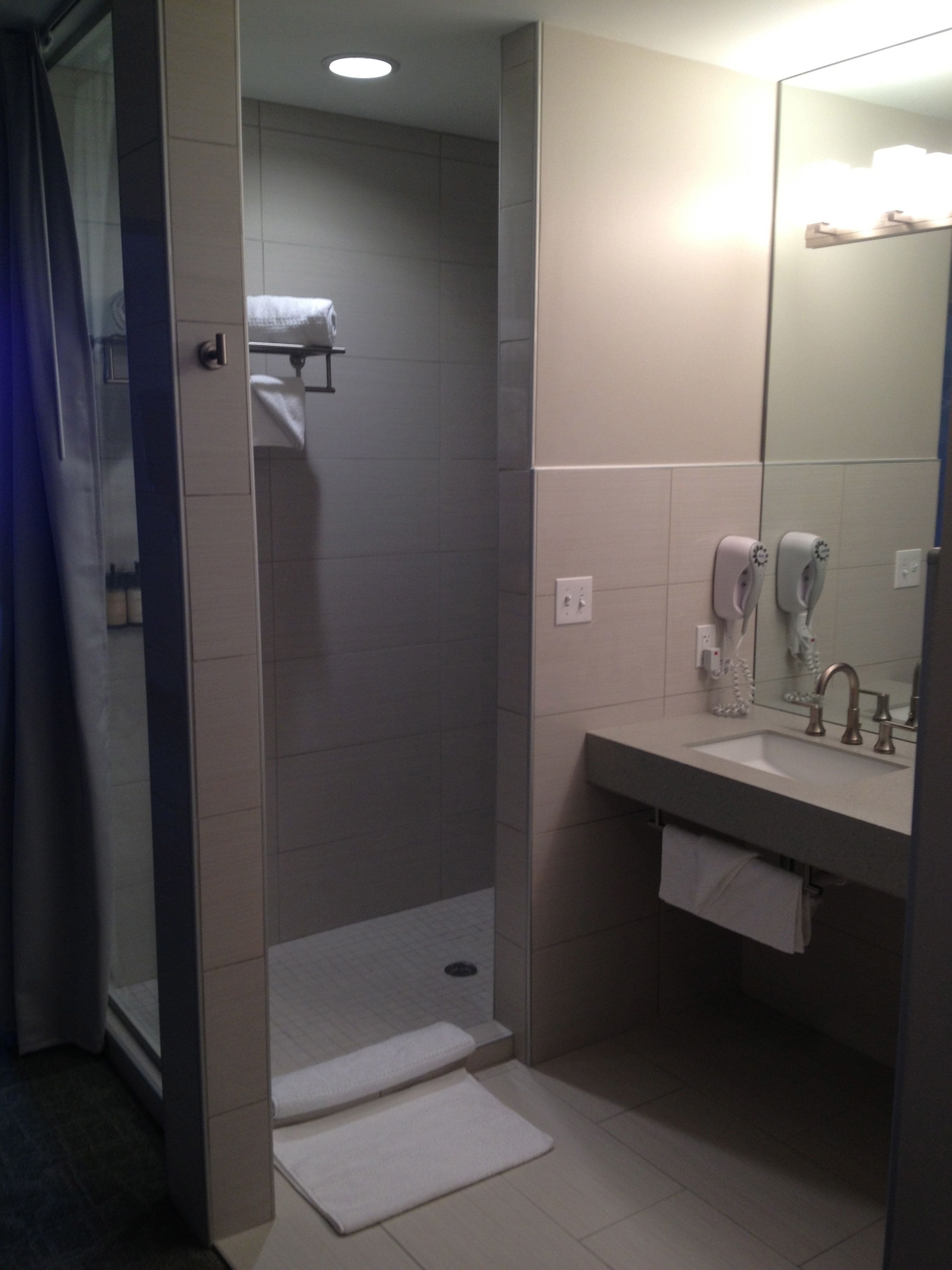 A modern bathroom with a walk-in shower, a sink with a mirror, and a towel rack.