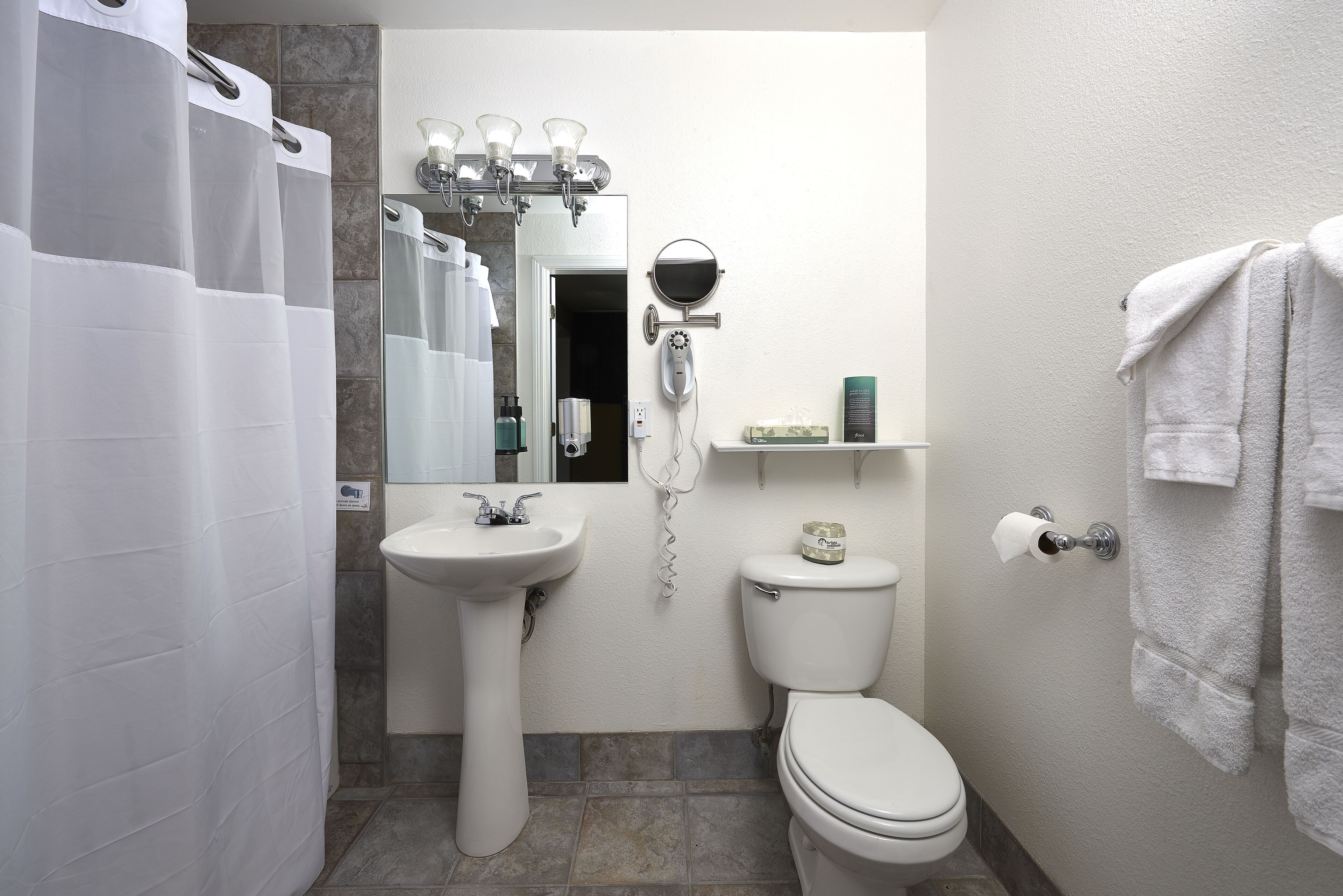 A bathroom with a sink, toilet, and shower curtain.