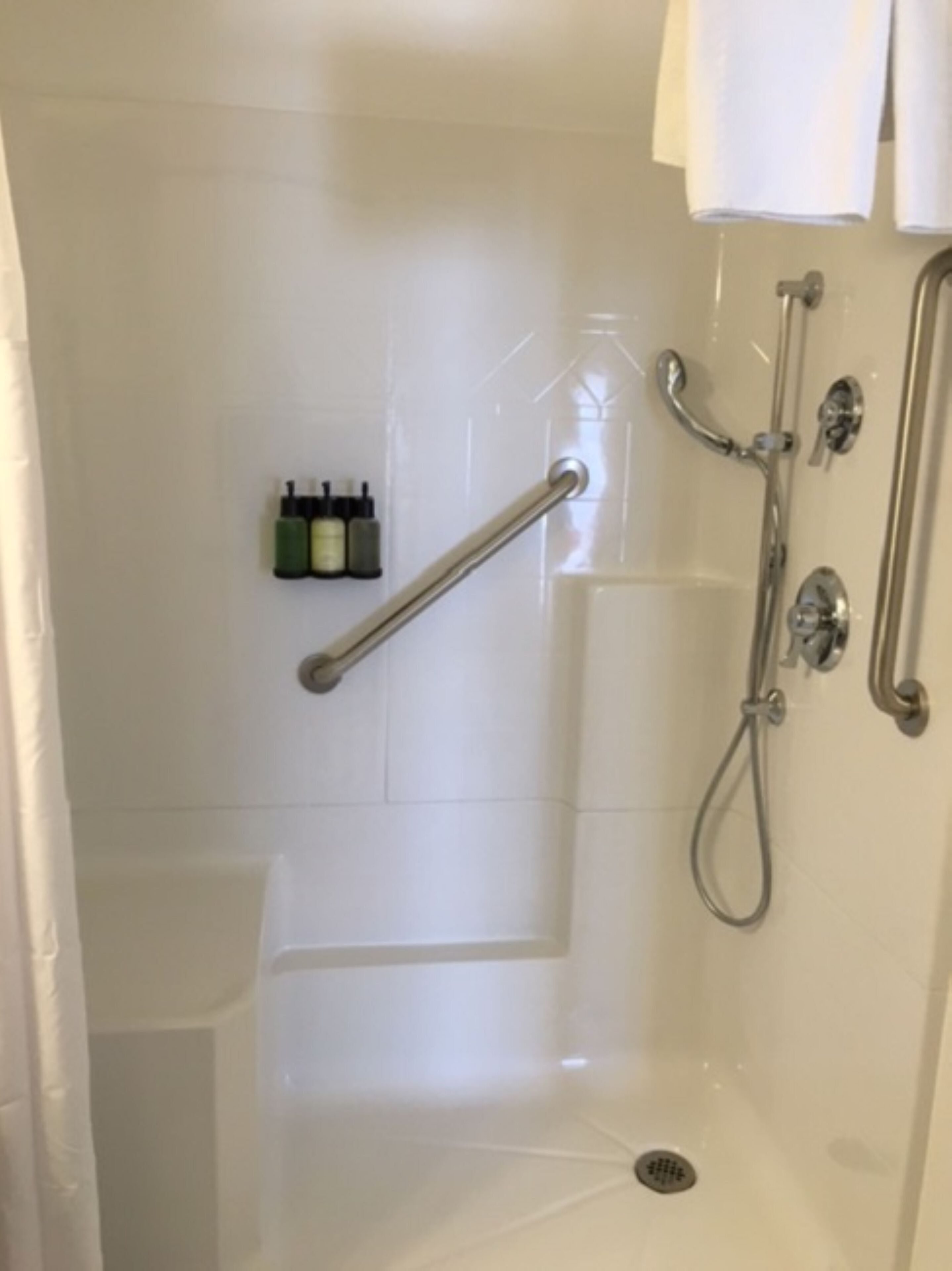 A modern bathroom with a walk-in shower, a handheld showerhead, and a handheld faucet.