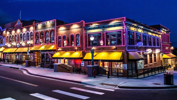 A historic building with multiple storefronts, including a restaurant and a bar, featuring classic architecture and neon signage.