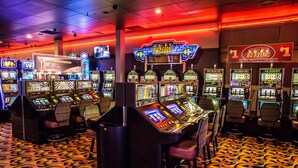 A casino with multiple slot machines, a hotel registration area, and a gold club sign.