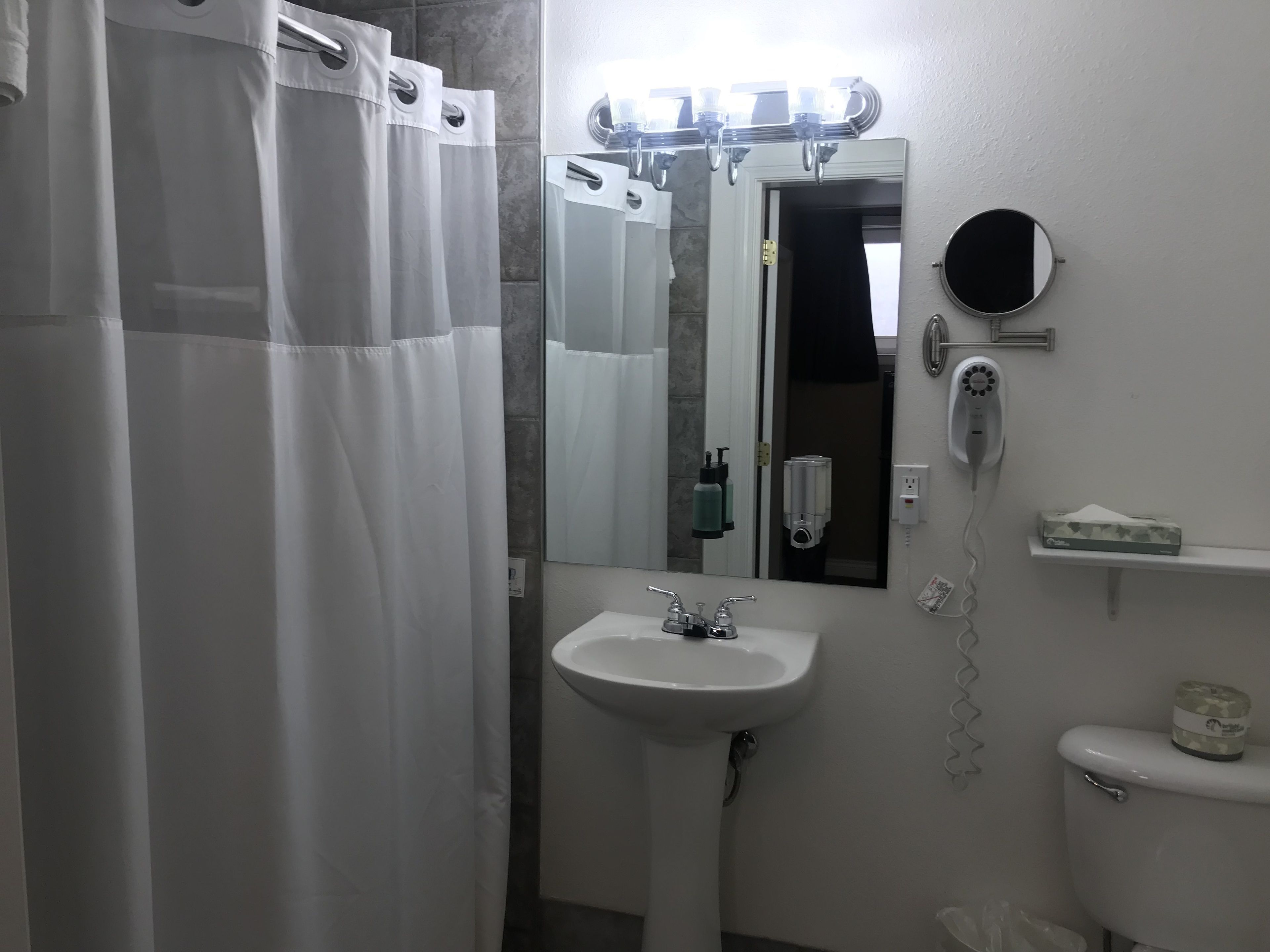 A bathroom with a white sink, a mirror, a toilet, and a shower curtain.