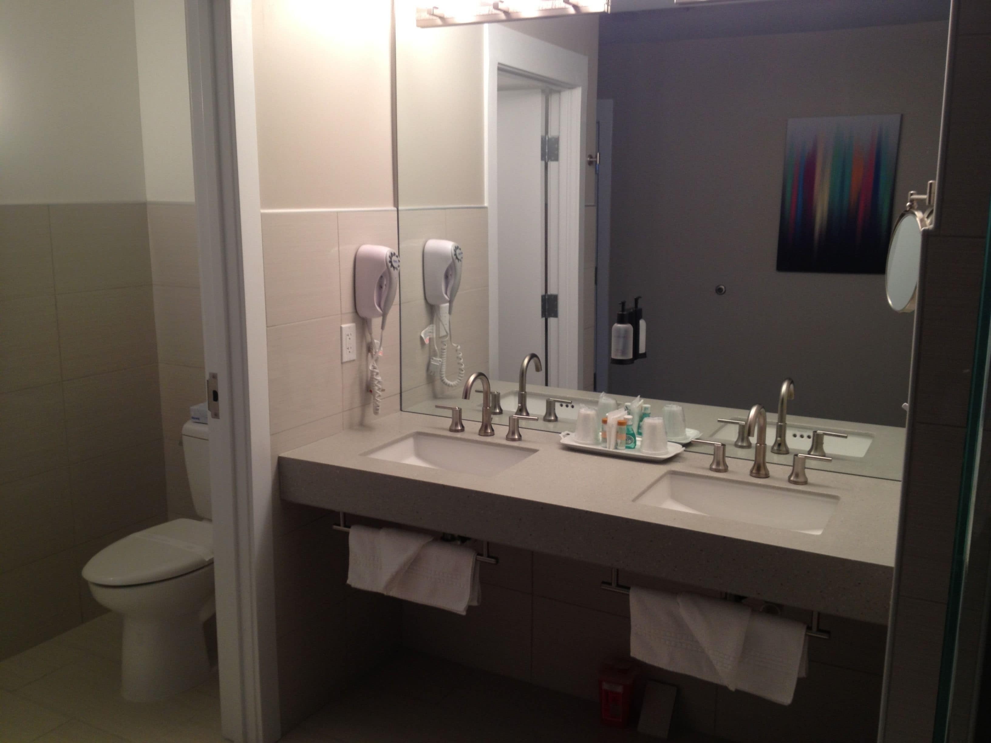 Un baño moderno con dos lavamanos, un secador de pelo y un espejo.