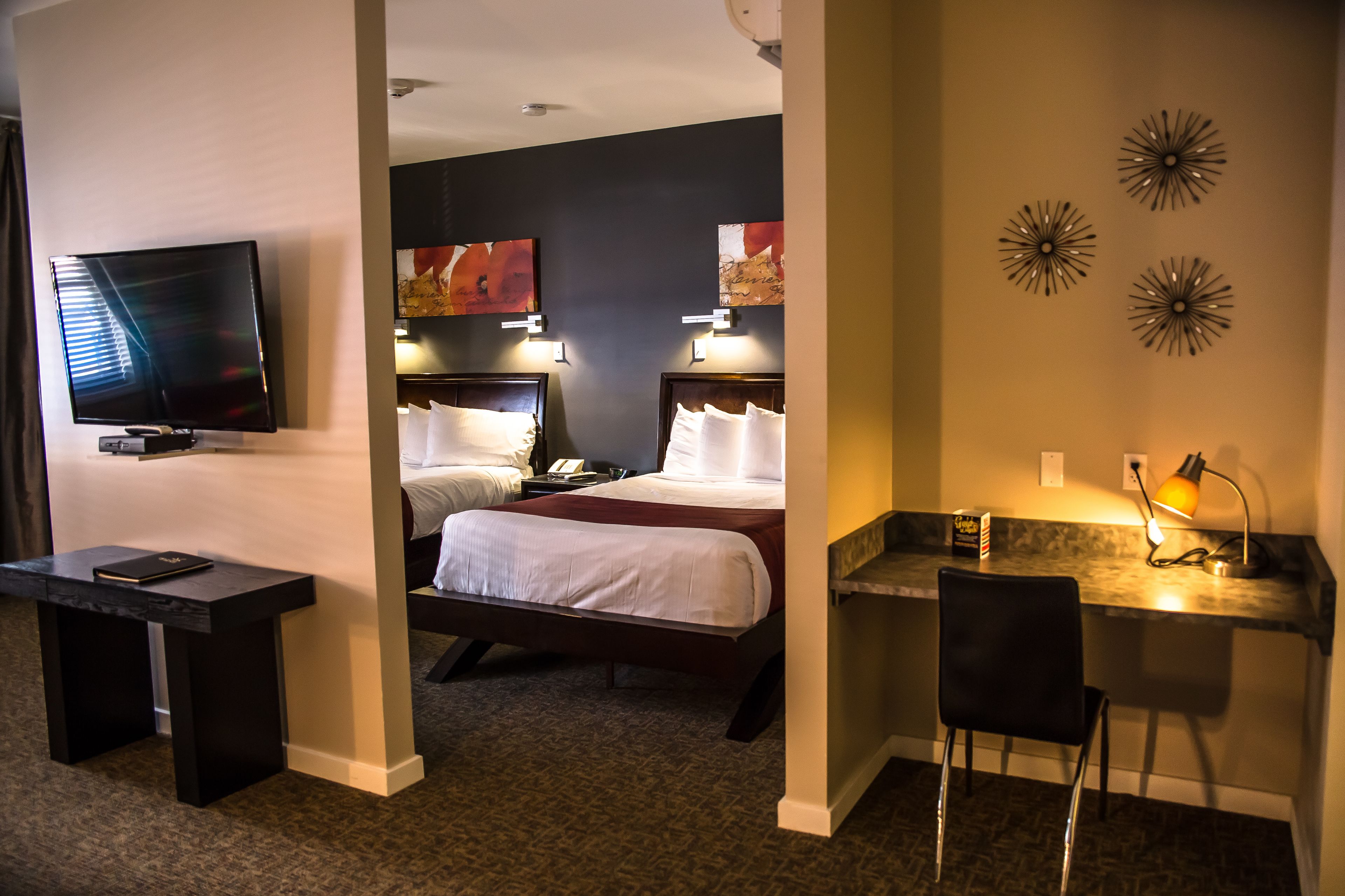 Ein Hotelzimmer mit Fernseher, zwei Betten, einem Schreibtisch und einem Sessel.