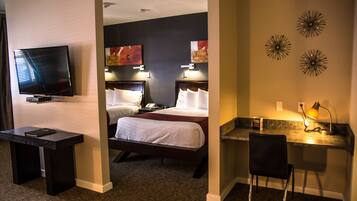 A hotel room with a TV, two beds, a desk, and a chair.