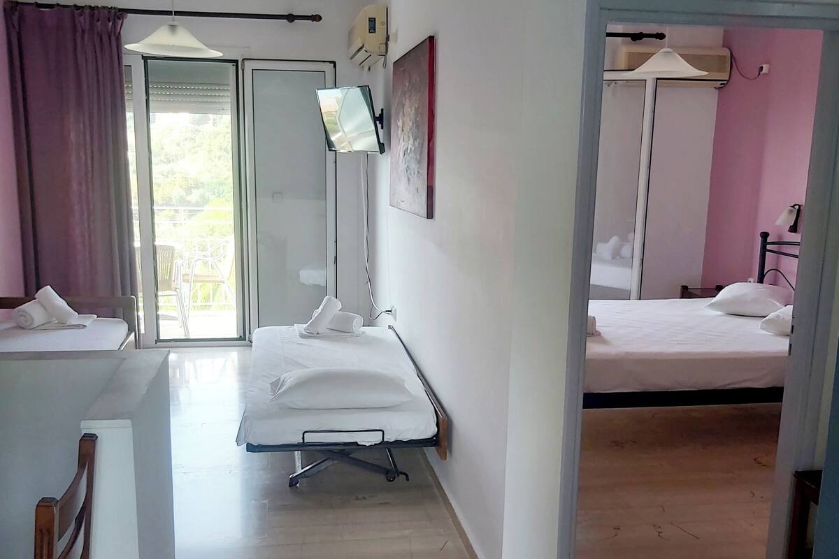 A hotel room with a bed, a desk, a chair, a TV, and a window with curtains.