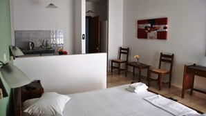 A hotel room with a bed, a desk, a chair, a small table, and a kitchenette. - Filoxenia Hotel & Apartments (Kefalonia)
